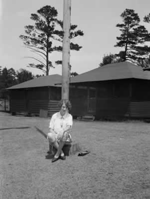 Elsie Stephens sitting at base of flagpole: Camp Highland, 1920s
